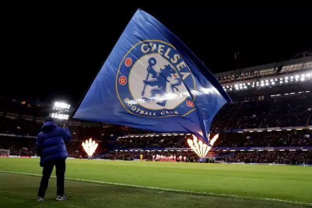 A flag waves at Stamford Bridge by night.