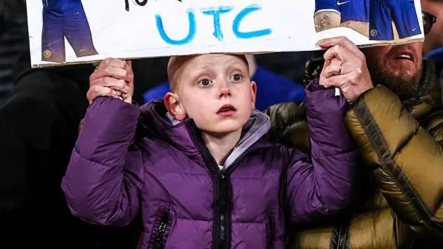 A young Chelsea fan holds up a pitiful sign.