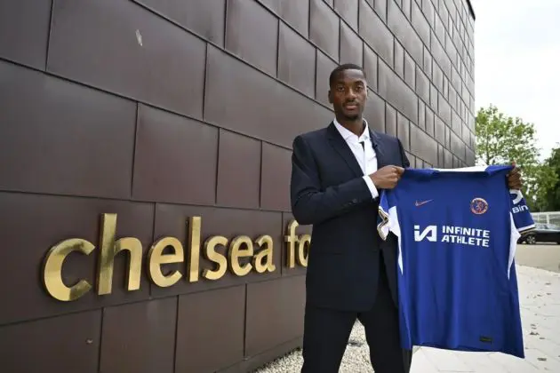 Tosin Adarabioyo holding a shirt up outside Cobham.