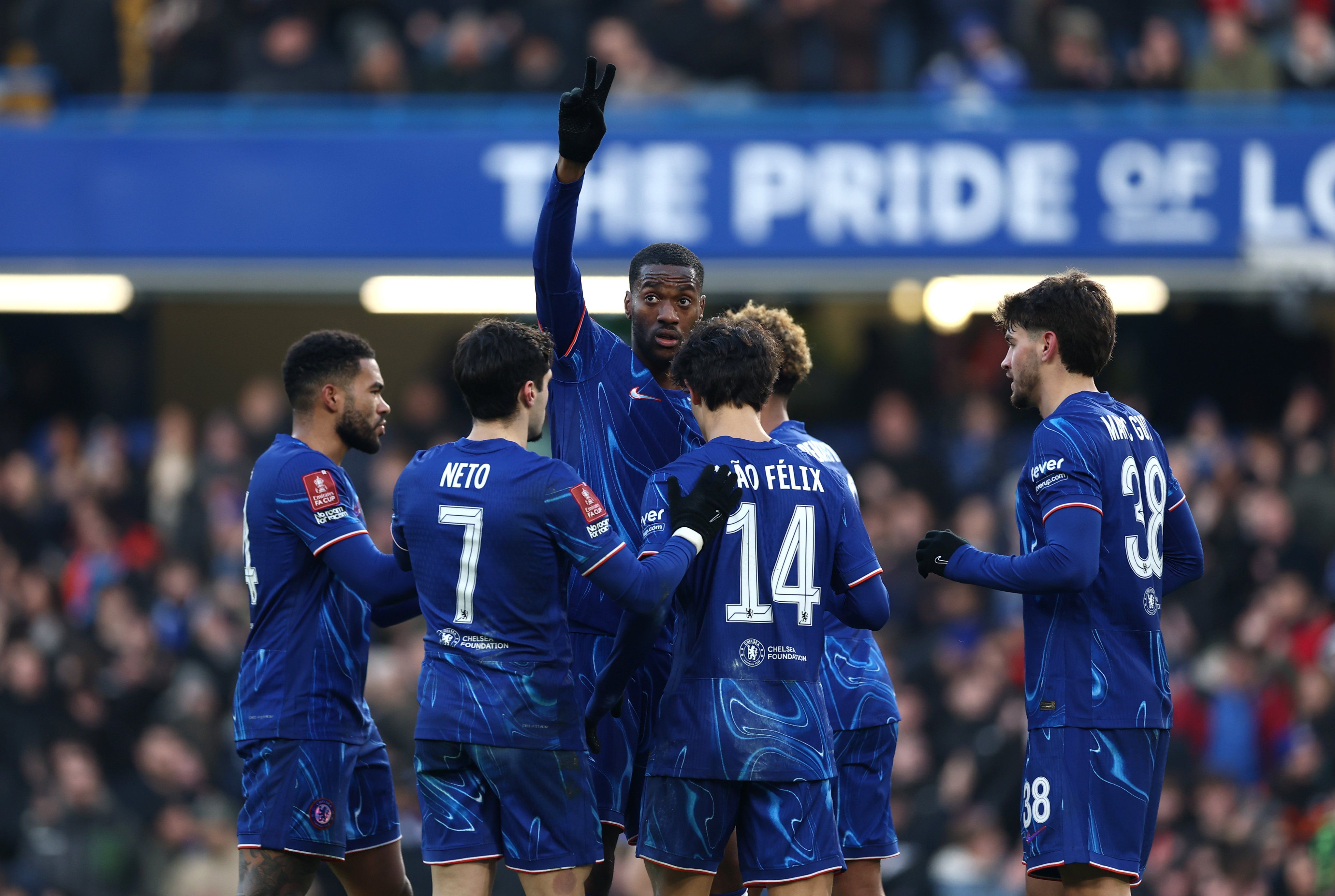 Tosin celebrates in a Chelsea group huddle after a goal in the FA Cup.